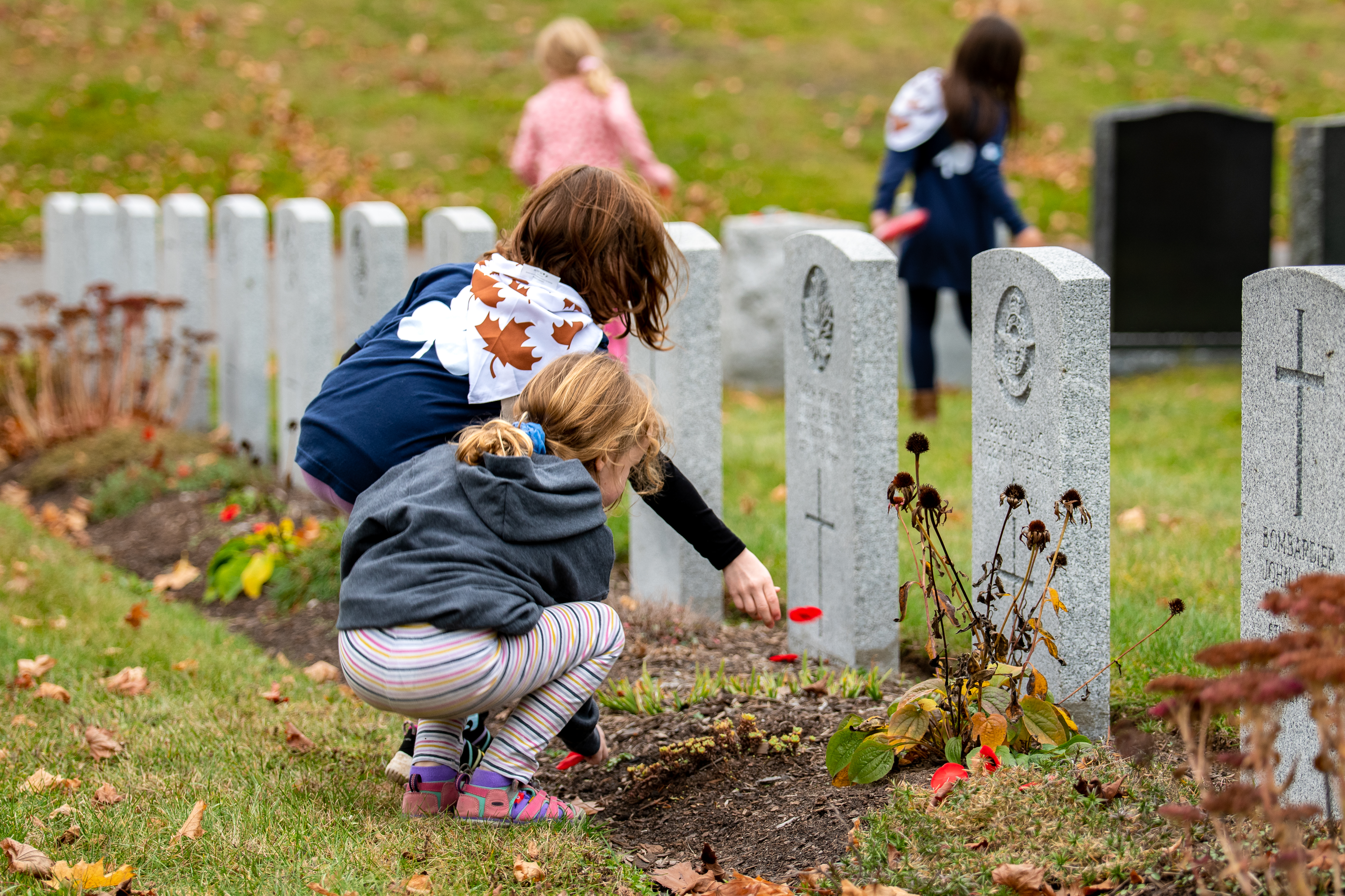 Girl Guide No Stone Left Alone - Guider placing a poppy on a headstone
