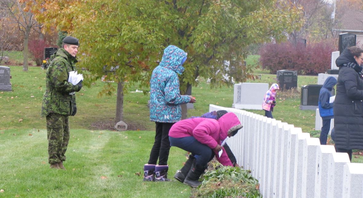 Child placing poppy on soldiers grave