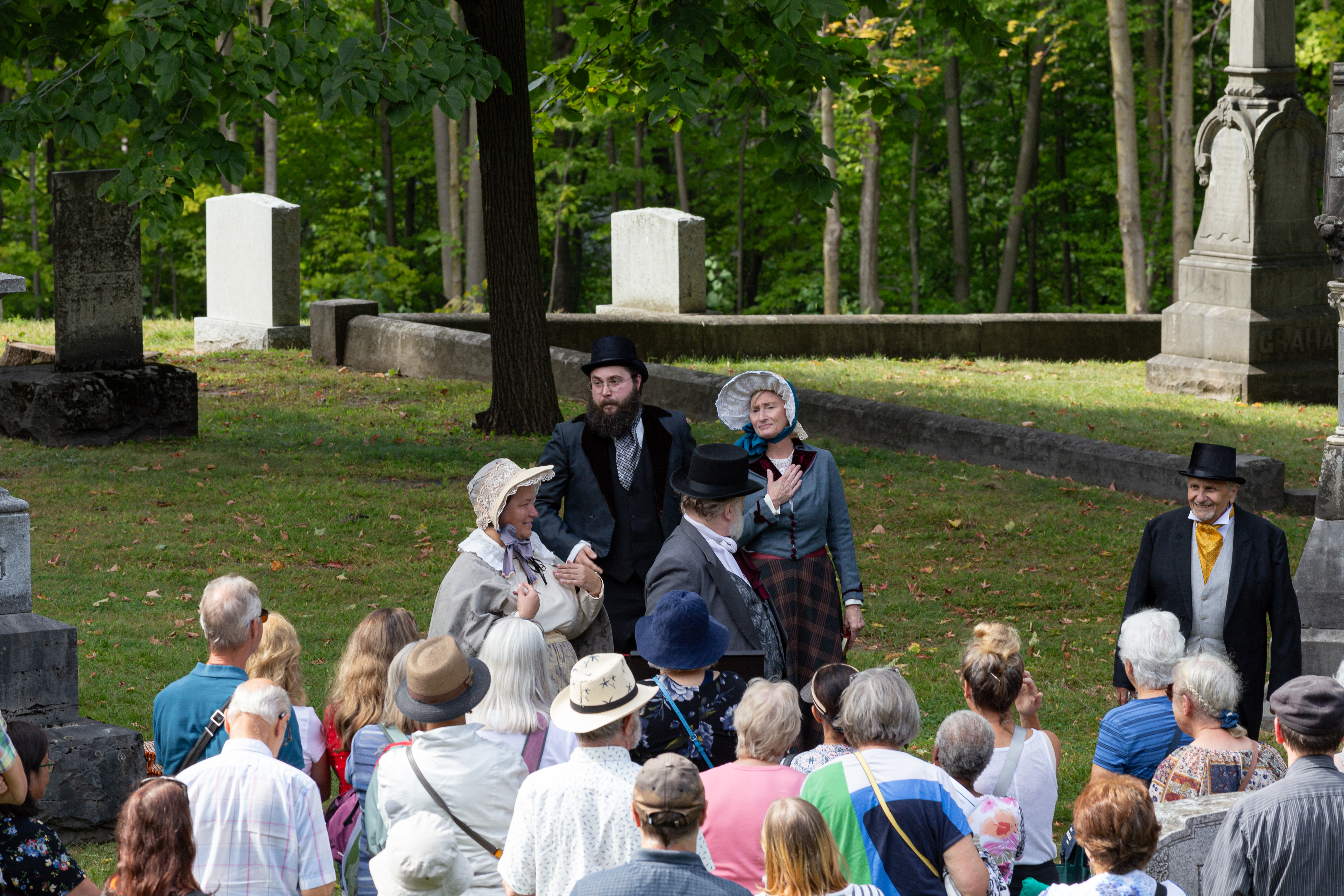 Tour photo of two actors speaking to a large group 