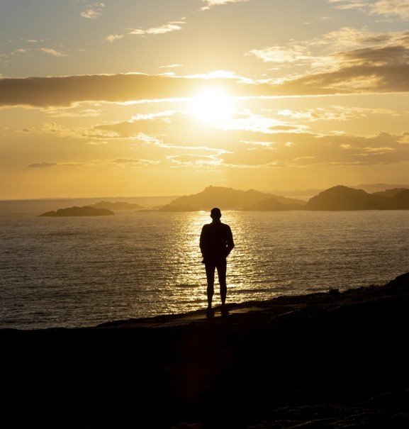 Silhouette of a person looking at a deep orange sunset.