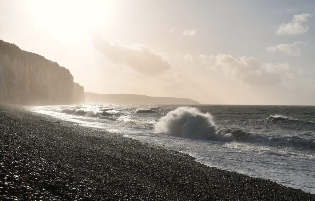 Coast in Dieppe in Normandy with waves and pebble beach in winter on late afternoon