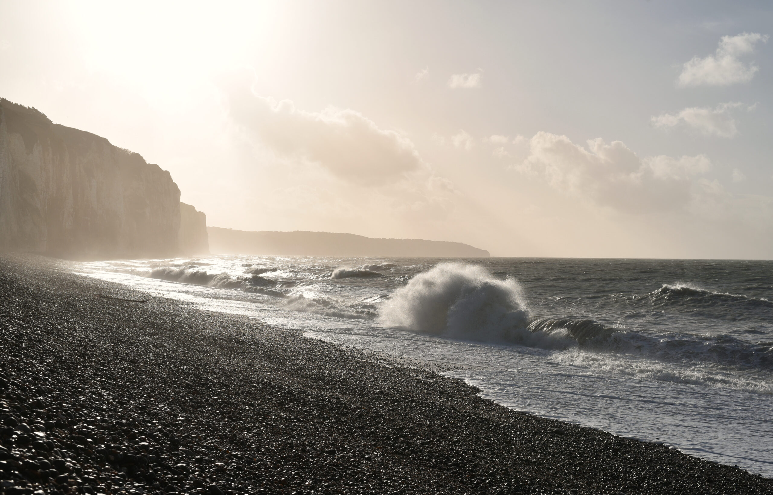 Coast in Dieppe in Normandy with waves and pebble beach in winter on late afternoon